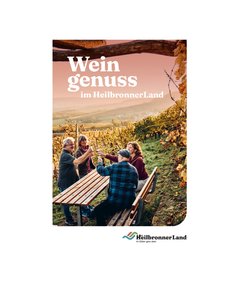 Vier Personen sitzen an einem Holztisch im Weinberg und stoßen mit Weingläsern an