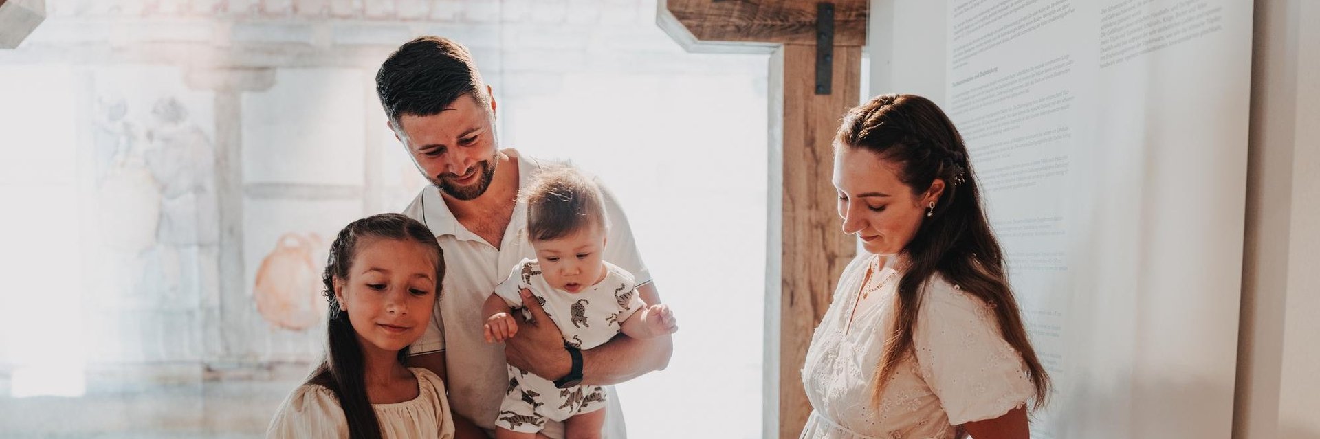 Familie mit zwei Kindern betrachtet Ausstellungsstücke in einem Museumsvitrinenschrank. 