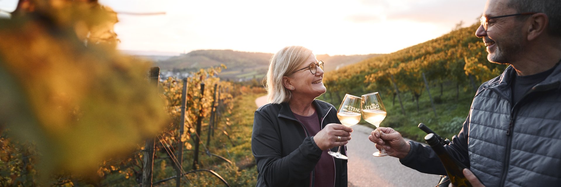 ein Pärchen stößt mir Weingläsern an und steht mit dem Rad in den Weinbergen 