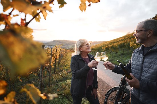 ein Pärchen stößt mir Weingläsern an und steht mit dem Rad in den Weinbergen 